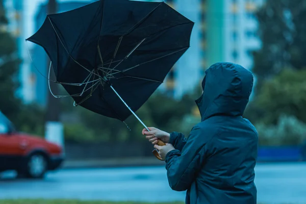 foto colorida de uma pessoa fugindo de uma tempestade de vendo - Metrópoles