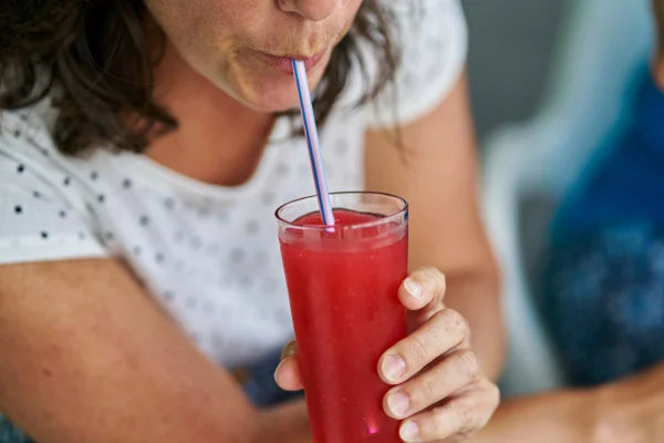 foto colorida de mulher bebendo suco de frutas vermelhas