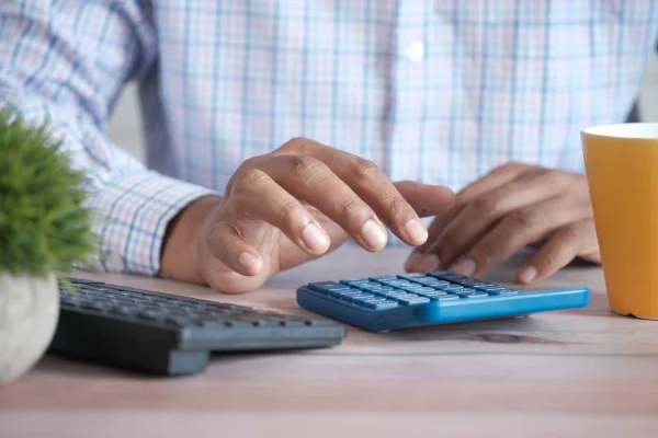 Fotografia colorida mostrando homem usando calculadora-Metrópoles