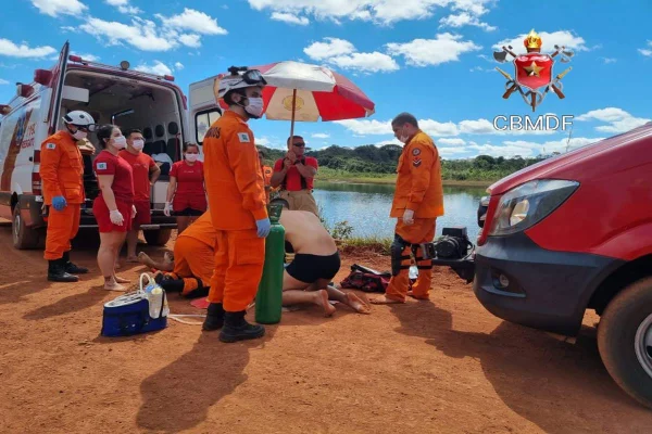 Foto colorida de bombeiros e samu fazendo resgate de jovem à beira de Lago - Metrópoles