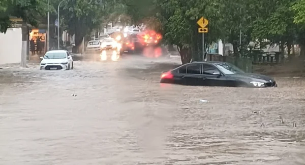 foto colorida de carros atravessando área alagada por chuva em rua da Pompeia, zona oeste de SP - Metrópoles