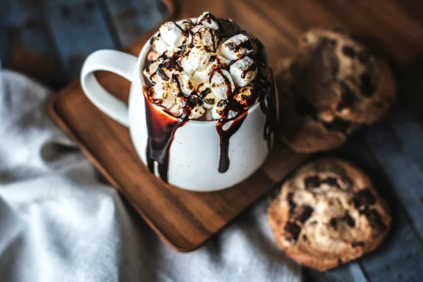 Como de chocolate quente com pedaços de marshmallow e cookles ao redor