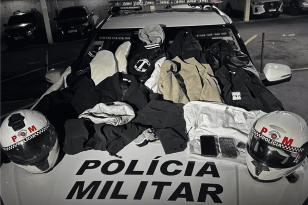 Imagem colorida de diversas peças de roupa apreendidas em uma viatura da Polícia Militar (PM) - Metrópoles