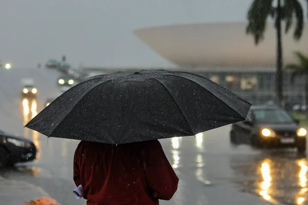 Foto colorida de pessoa usando guarda-chuva em Brasília - metrópoles