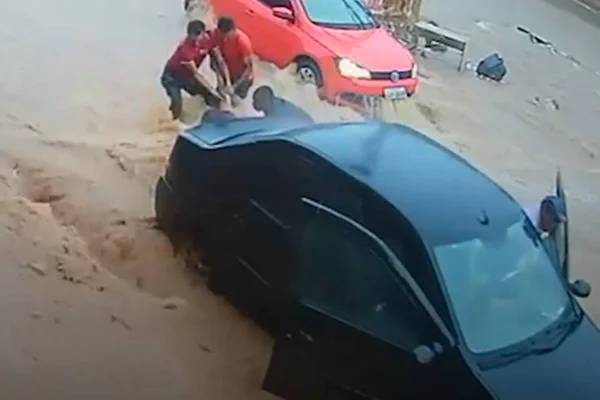 Foto de homens salvando mulher presa debaixo de carro