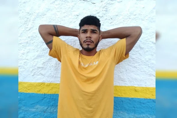 Imagem colorida mostra Eustácio Batista Dias, um homem negro, com uma camiseta amarela e os braços atrás da cabeça - Metrópoles