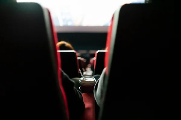 Imagem de sala de cinema, com poltronas vistas de trás e pessoas sentadas assistindo a um filme - Metrópoles