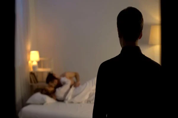 Foto colorida de um homem e um casal se beijando na cama - Metrópoles