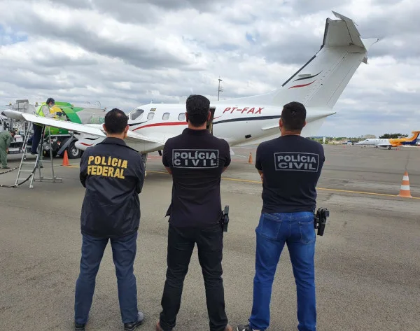 Homens da polícia em frente a avião.