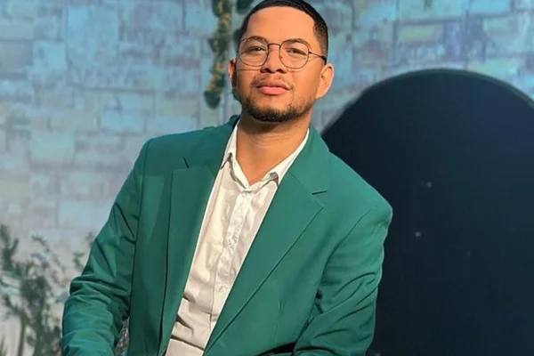 O cantor gospel Pedro Henrique posa de blusa branca, blaser verde e óculos - Metrópoles