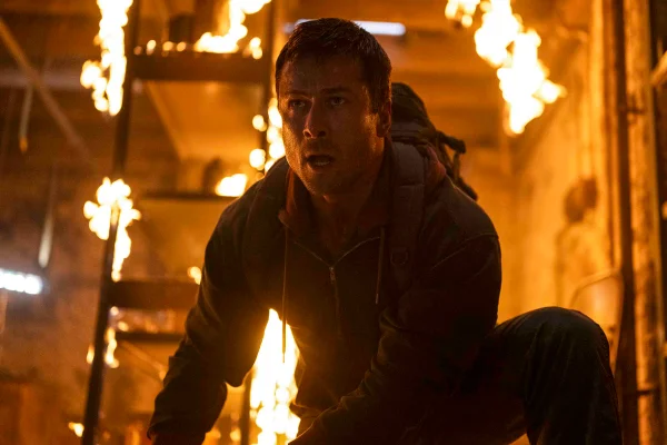 Imagem colorida de Glen Powell em cena do filme O Sobrevivente
