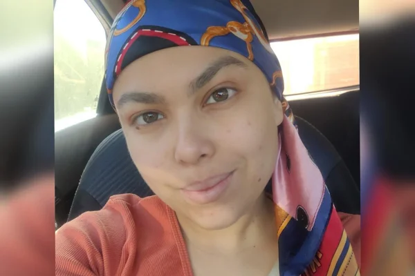 Foto colorida de mulher com lenço azul na cabeça e blusa vermelha - Metrópoles