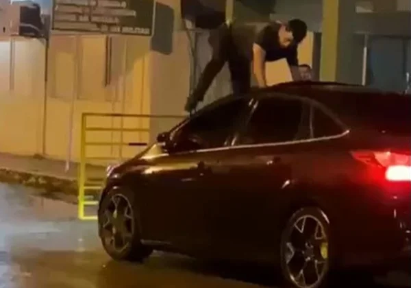 Imagem colorida onde um ex-marido persegue mulher em cima de capô de carro - Metrópoles