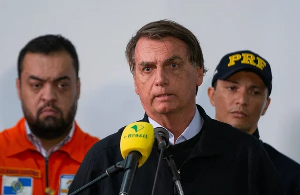 Bolsonaro afirmou que a população tinha razão em criticar após nova tragédia em Petrópolis. Ele fala no microfone, cercado de autoridades, e usa jaqueta preta - Metrópoles