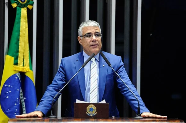 Imagem colorida mostra o senador Eduardo Girão, de terno azul, em um púlpito em frente a uma bandeira do Brasil. Ele anuncia que vai concorrer à presidência do Senado - Metrópoles