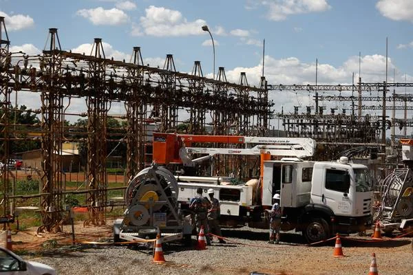 Fotografia colorida de caminhão em frente à subestação de energia