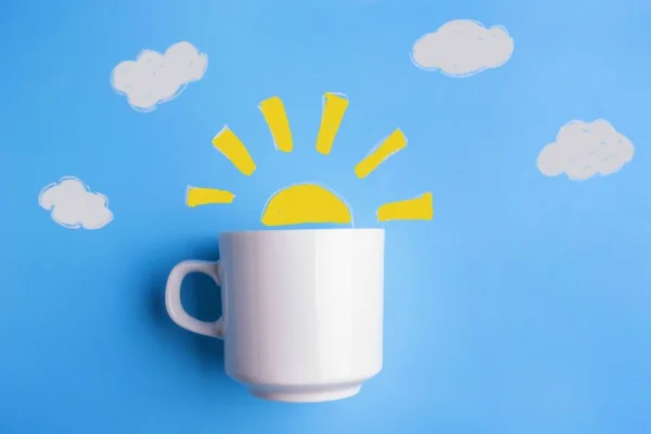 uma foto de um desenho do sol com uma xicara de café