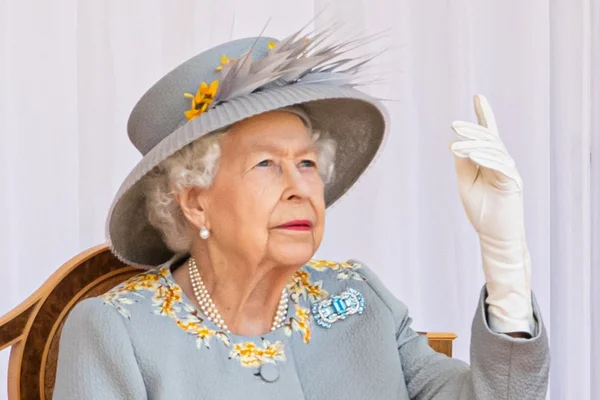 Foto colorida. Rainha Elizabeth com a mão levantada