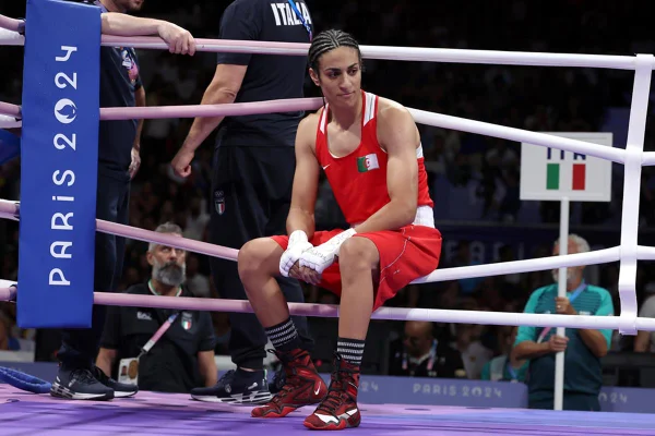 Imagem mostra a atleta Imane Khelif, de uniforme vermelho, sentada nas cordas do ringue de boxe nas Olimpíadas de Paris - Metrópoles