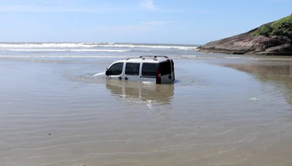 Homem pega carro de amigo, atola em praia e veículo fica submerso - destaque galeria