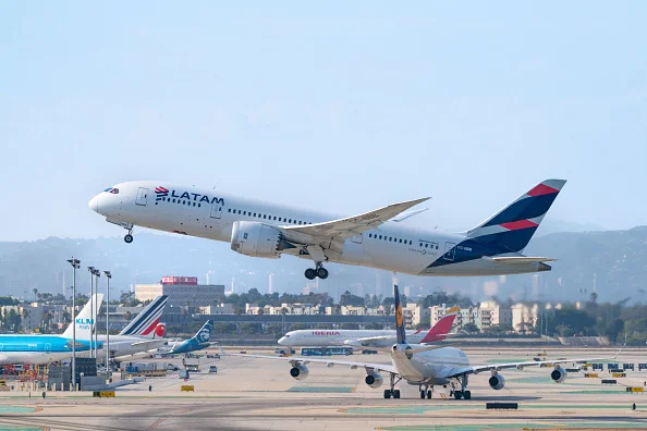 Imagem de colorida de avião da Latam decolando de aeroporto, em dia de céu azul e tempo aberto - Metrópoles