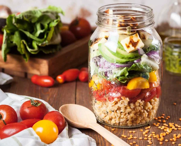 Foto colorida de um pote de vidro que contém uma salada com alimentos ricos em vitamina B