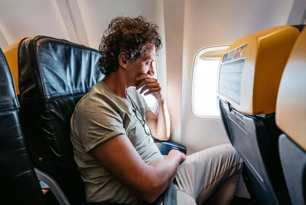Homem com medo de viajar de avião olhando pela janela - Metrópoles