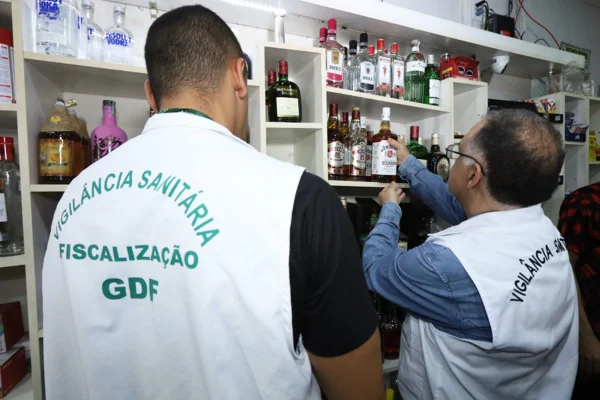 Imagem colorida de fiscais da vigilância sanitária verificando bebidas