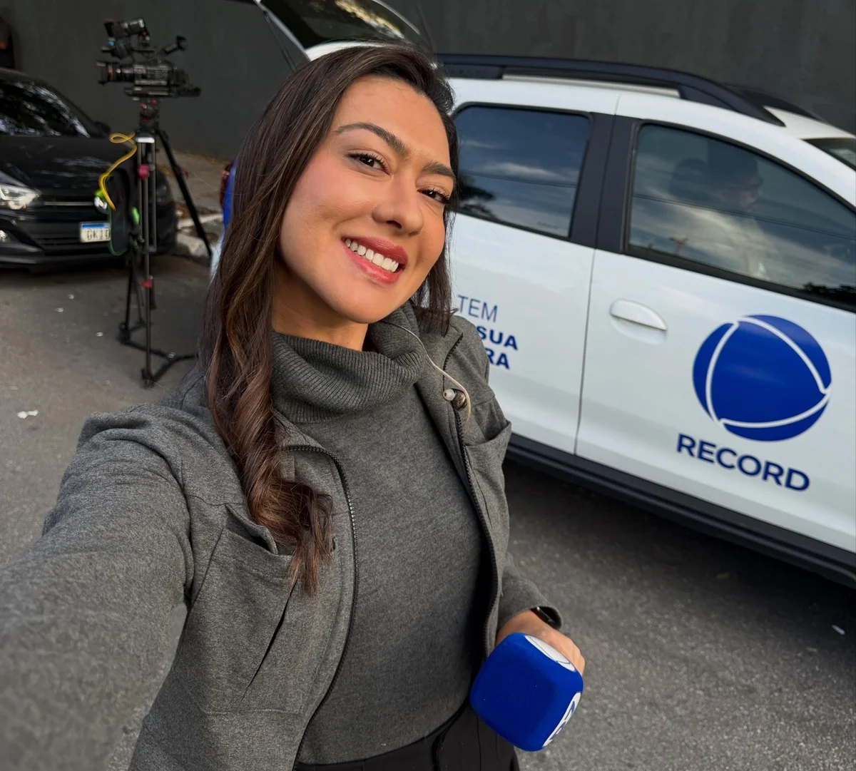 Repórter da Record, Paola Vianna faz selfie ao lado de carro da reportagem Repórter da Record, Paola Vianna faz selfie ao lado de carro da reportagem