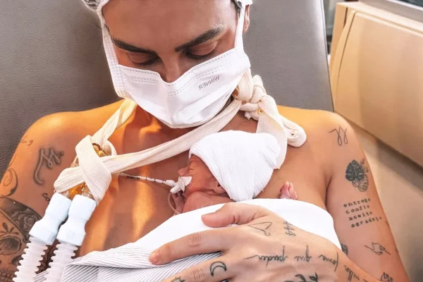 Imagem colorida da influenciadora Clara Maia segurando o filho prematuro, Théo, no colo