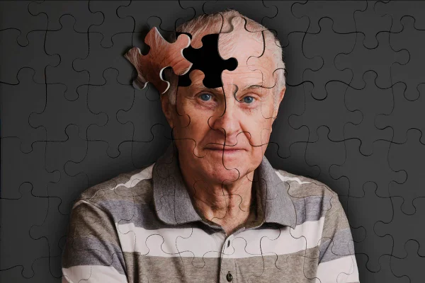 Foto de quebra-cabeça com a foto de um idoso. Falta uma peça bem na parte da cabeça do cabeça