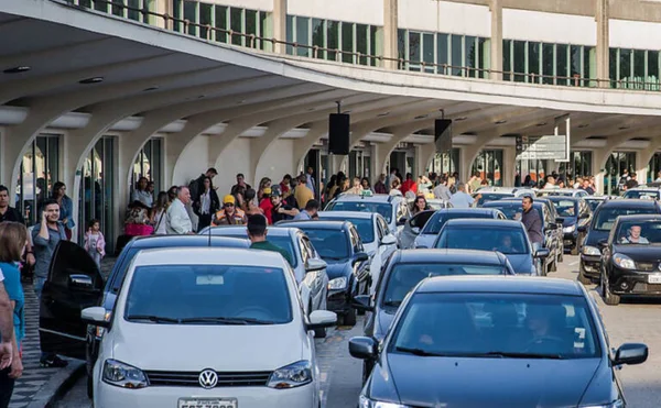 Imagem de via de acesso de aeroporto lotada de carros e passageiros - Metrópoles