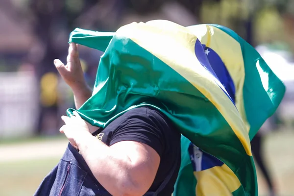 Manifestante pró-Bolsonaro com bandeira no rosto