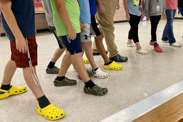 A imagem mostra sete jovens exibindo suas Crocs, sem exibir o rosto dos fotografados