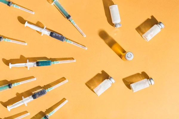 Seringas e fracos com substâncias mésicas em um fundo amarelo. São os utensílios necessários para aplicar injeções e vacinas