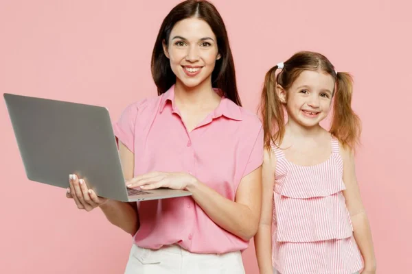 Mulher segurando um notbook com camisa rosa e uma menininha tbm usando roupa rosa