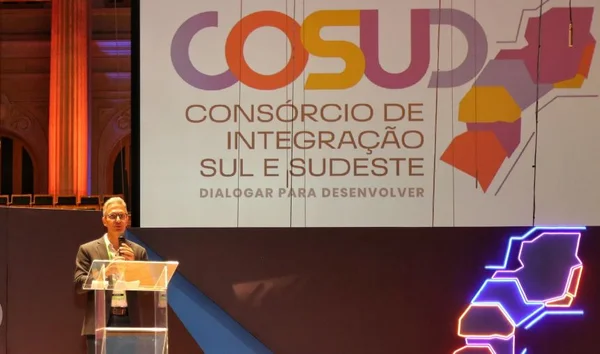 Foto colorida do governador Romeu Zema, de Minas Gerais, discursando no palco da Sala São Paulo com o painel do Consórcio Integração Sul e Sudeste ao fundo - Metrópoles