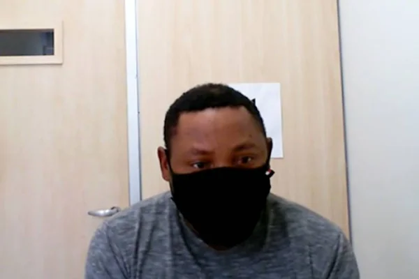 homem negro de blusa cinza e máscara preta