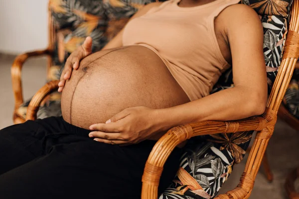 Imagem mostra mulher negra grávida sentada em uma cadeira - Metrópoles