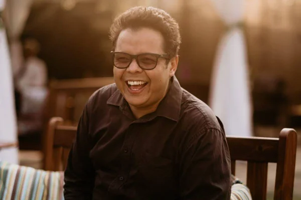 foto colorida de homem sorrindo de oculos - metrópoles