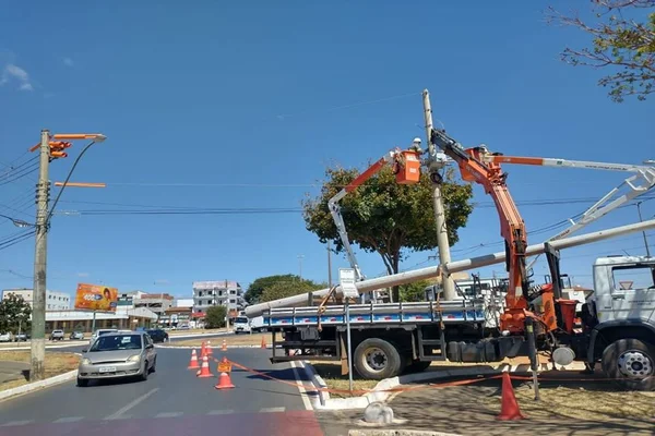 Homem com capacete de segurança, dentro de elevação móvel mexe em fiação elétrica