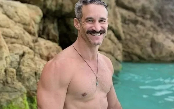 homem sem camisa sorrindo em praia