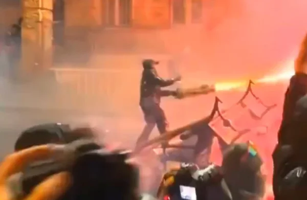 Imagem colorida de manifestantes kogando fogos de artifício contra canhões de água - Metrópoles