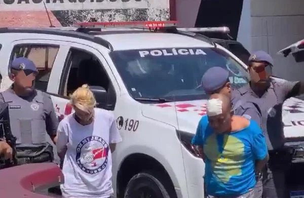 Em foto colorida casal é escoltado por policias militares - Metrópoles