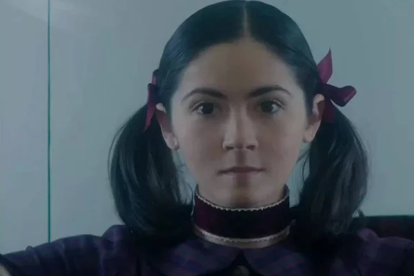 Isabelle Fuhrman, atriz que interpreta a personagem Esther em cena do filme "A Orfã 2". Ela usa maria-chiquinhas com laços, uma gargantilha e vestido, olhando para frente - Metrópoles