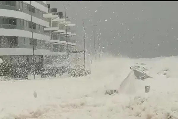 Forte geada no Uruguai, onde prédio e rua são cobertos pela neve, com céu cinza ao fundo - Metrópoles