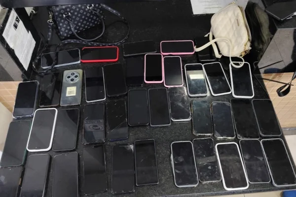 Imagem colorida de celulares e itens furtados em cima de uma mesa. Metrópoles