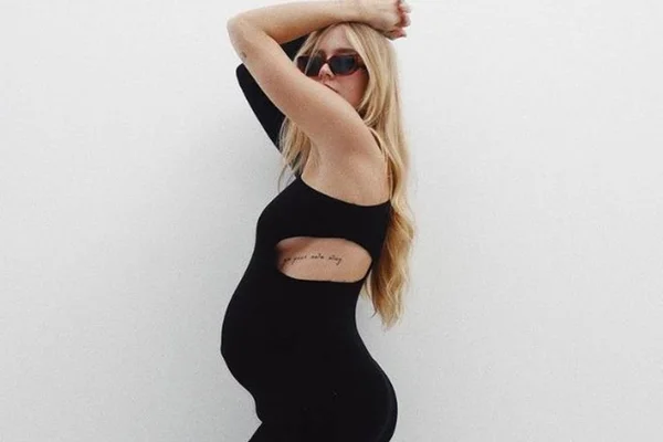 foto colorida de uma mulher grávida com os braços levantados