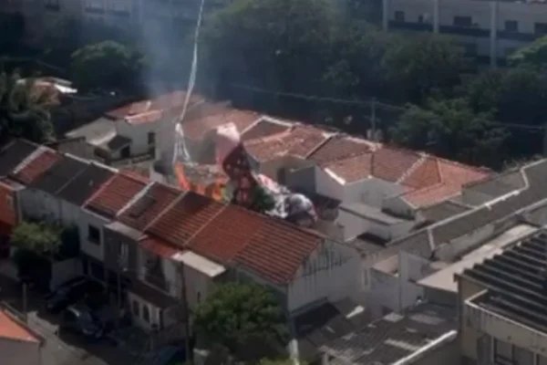 Imagem colorida de balão pegando fogo logo após cair entre 3 casas. Metrópoles