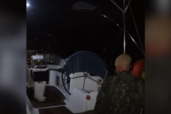 Imagens coloridas mostram policial militar ambiental dentro de veleiro, durante a noite
